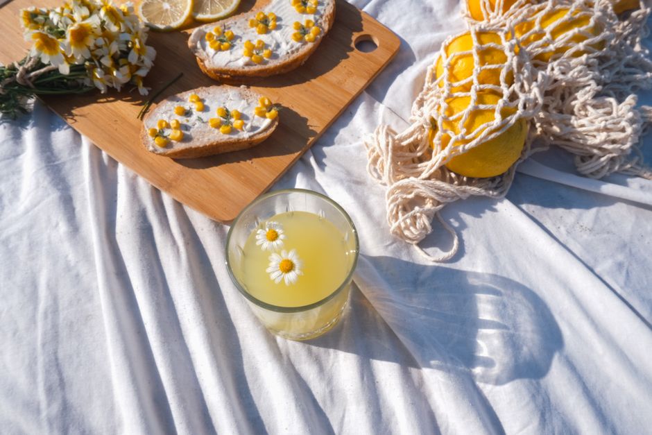 Refreshing lemonade with daisies on a cutting board, perfect for a summer picnic.