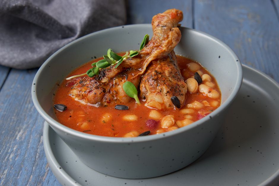 Savor the taste of hearty chicken and bean stew served in a blue ceramic bowl.