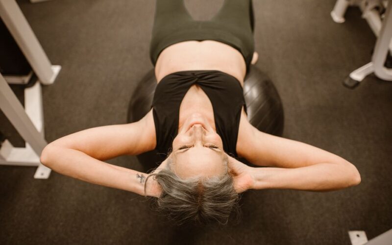 Senior woman performing exercise on stability ball for fitness and strength.