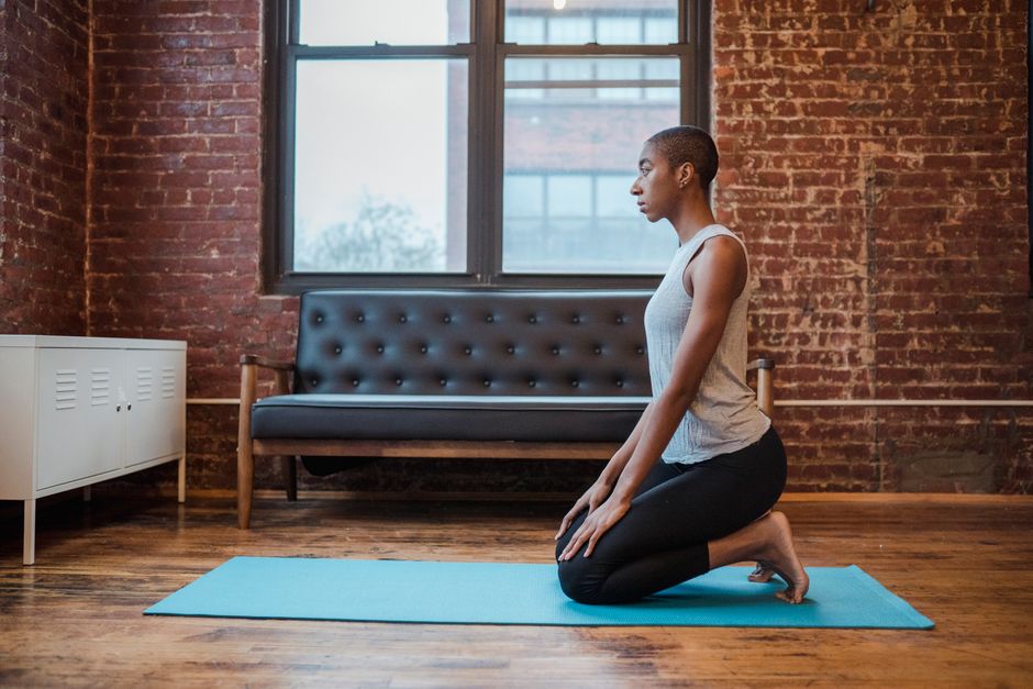 Side view full body of concentrated African American female in activewear practicing Vajrasana during stress relief yoga session