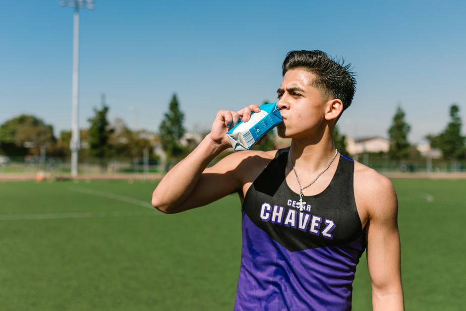 Teen athlete hydrating with a sports drink during an outdoor workout.