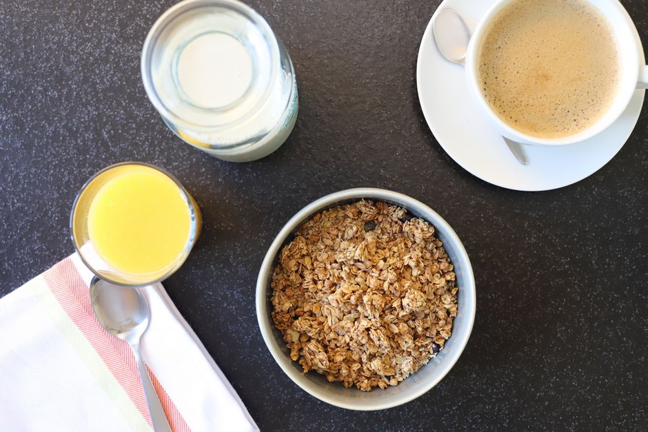 Top-down view of a nutritious breakfast featuring granola, coffee, and orange juice.