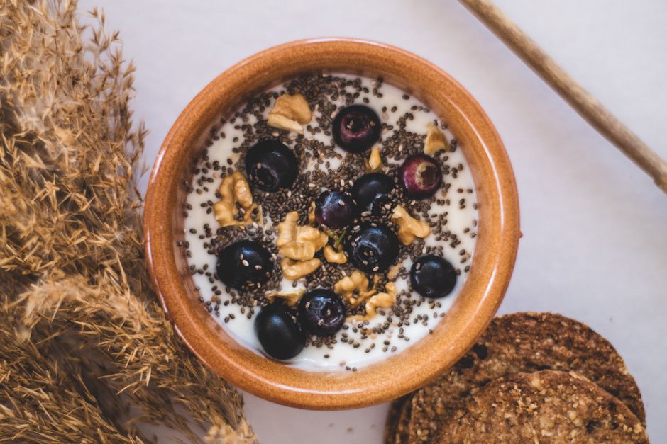 Top view of a nutritious bowl with yoghurt, blueberries, chia seeds, and walnuts.
