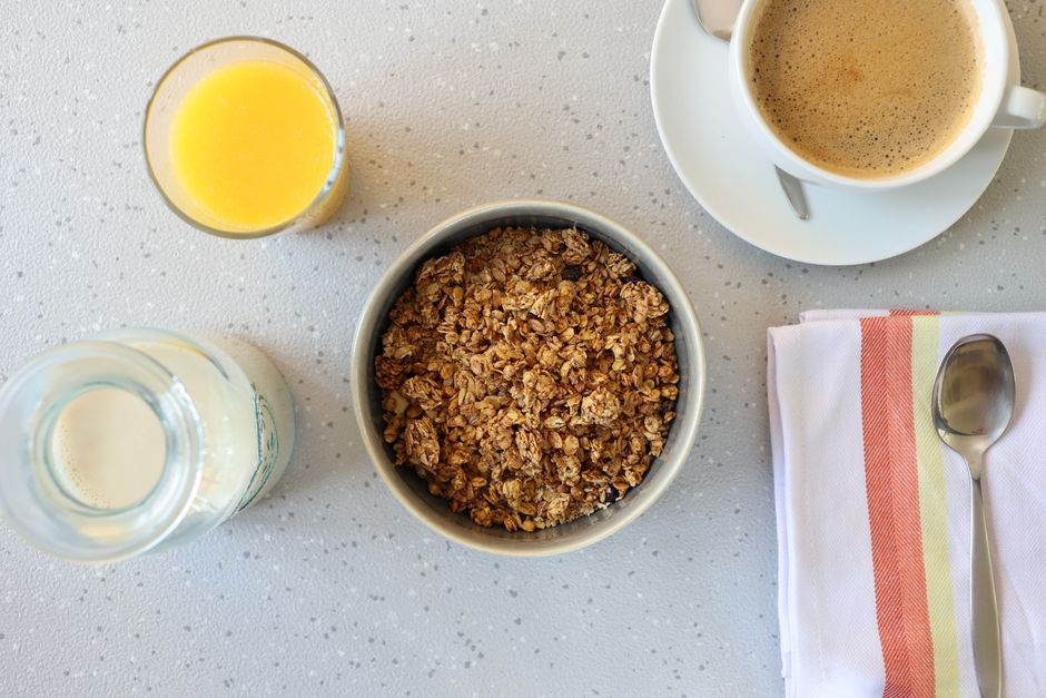 Top view of a nutritious breakfast setup including granola, orange juice, and a cup of coffee.