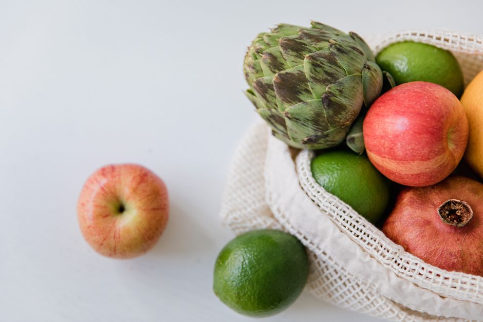 Top view of assorted fresh fruits and vegetables on a white surface, perfect for promoting healthy eating.