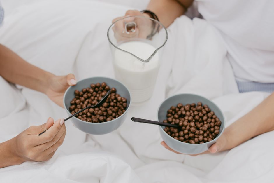 Top view of two people enjoying chocolate cereal with milk for breakfast.