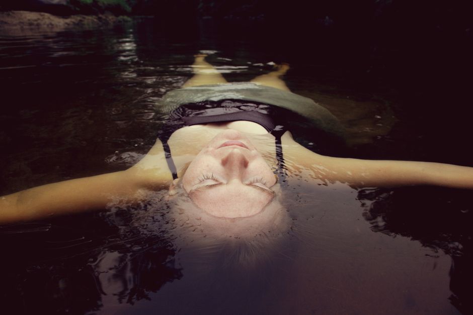 Tranquil scene of a woman floating on water, capturing peaceful relaxation in nature.