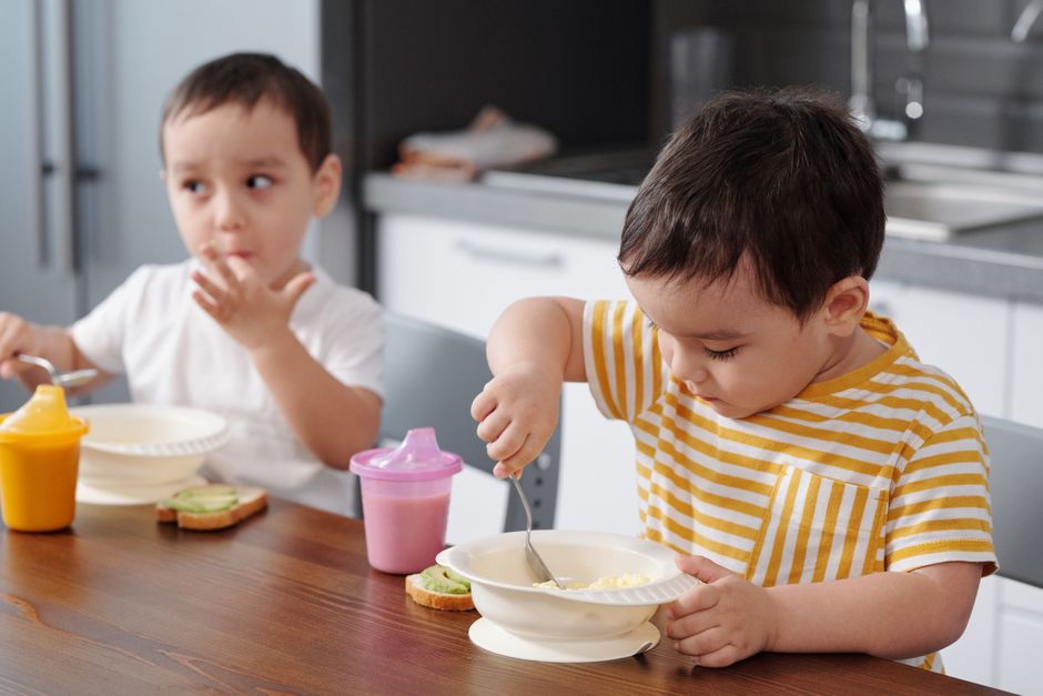 Two children enjoying breakfast together in a cozy home kitchen setting.