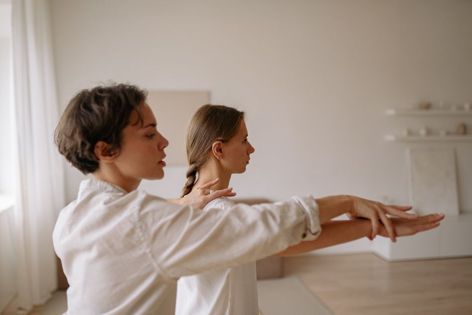 Two women practicing mindful movement exercises in a serene indoor setting.