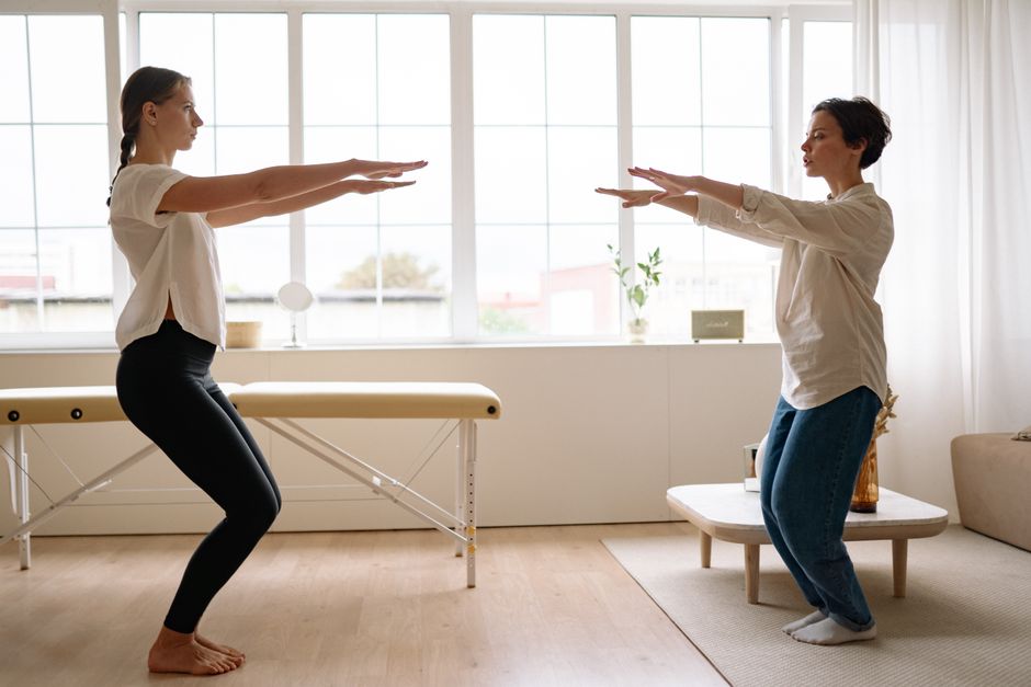 Two women practicing yoga together in a bright, airy room, focusing on fitness and wellness.
