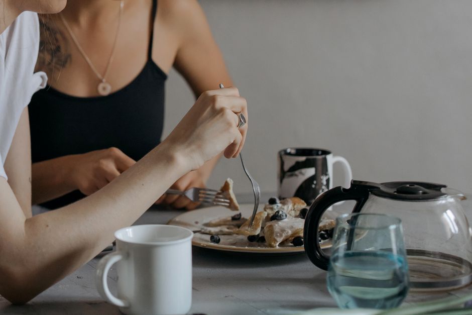 Two women savoring breakfast with pancakes and coffee, creating a cozy morning scene.