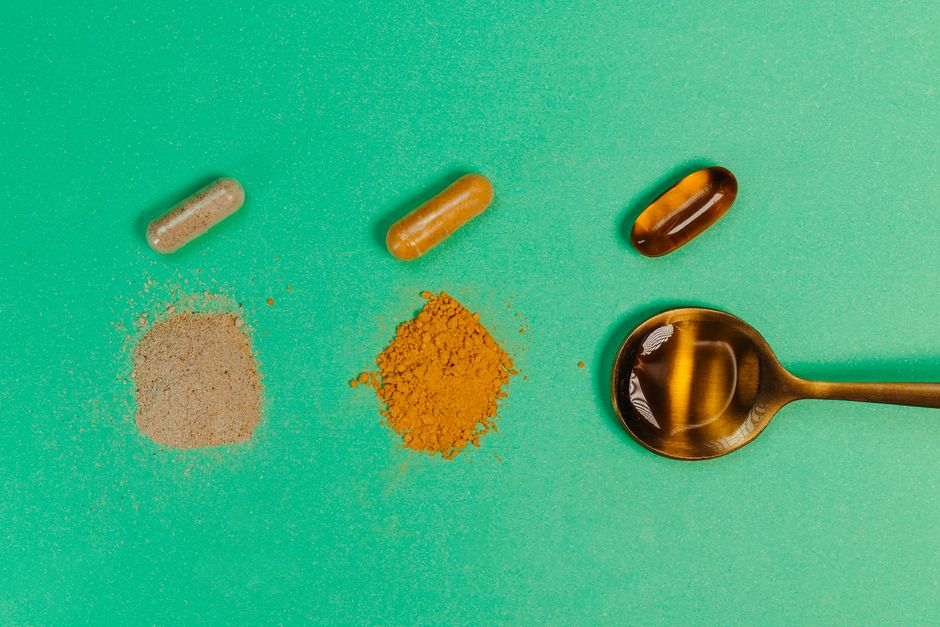 Various nutritional supplements and powders displayed with a spoon on a green background.