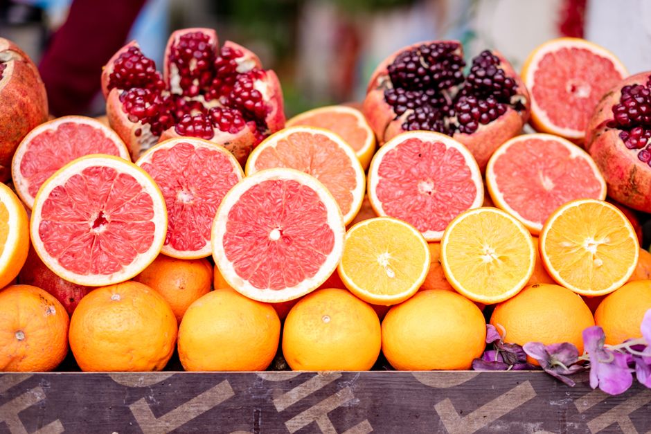 Vibrant display of sliced grapefruits, oranges, and pomegranates showcasing fresh and healthy tropical fruits.