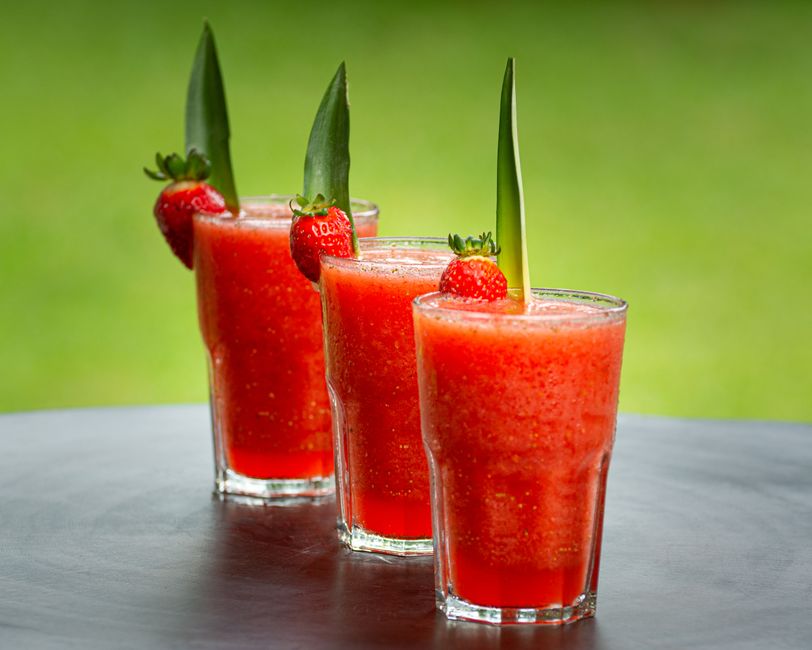 Vibrant strawberry smoothies garnished with pineapple leaves, perfect for summer refreshment.