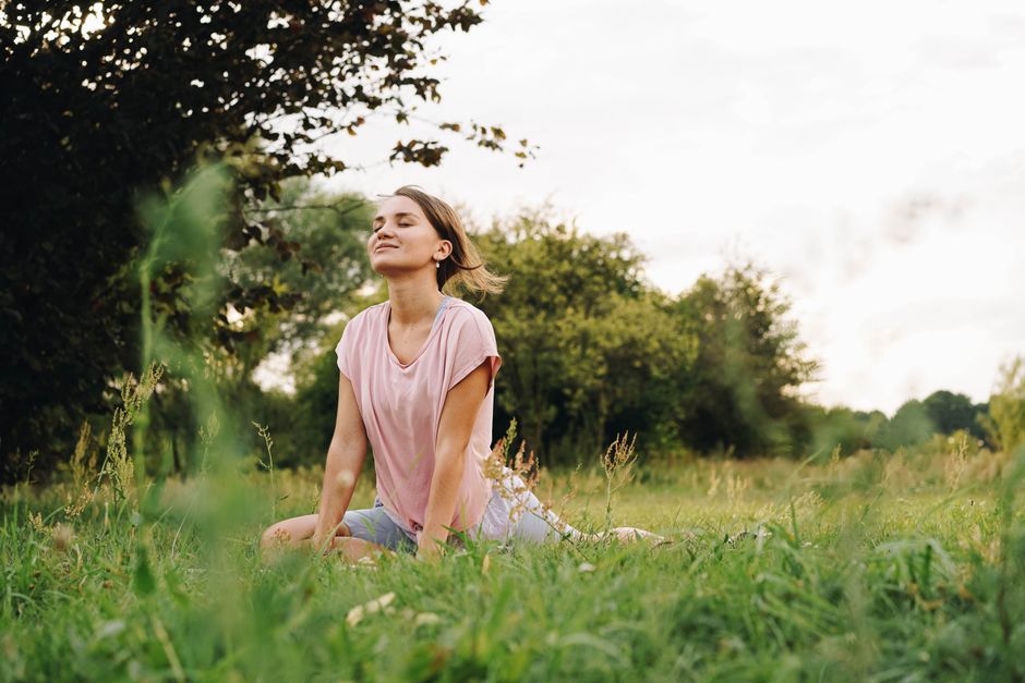 Woman practicing yoga in a serene park setting, signifying peace and mindfulness.