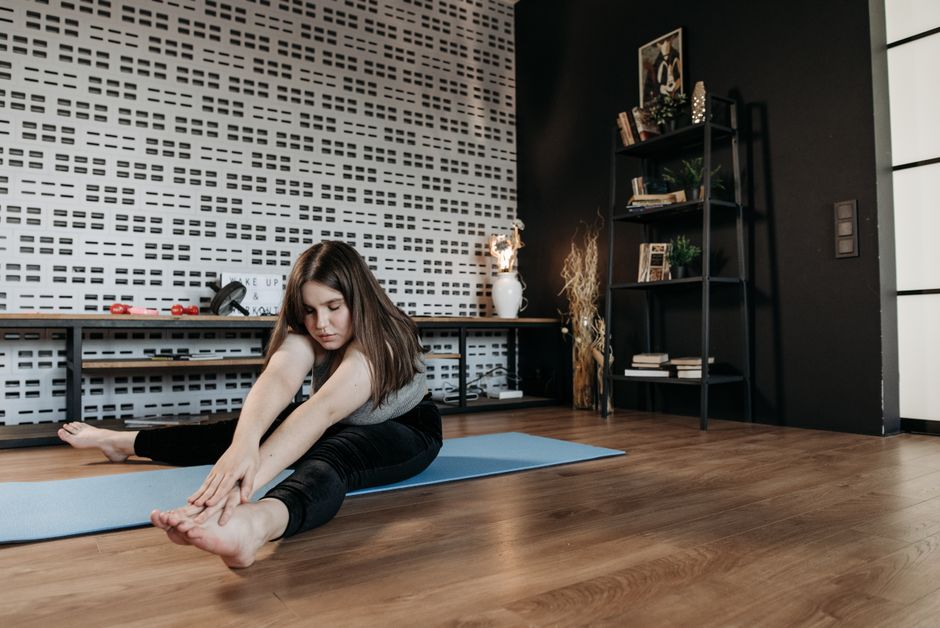 Woman practicing yoga stretch on mat in modern home interior. Promotes wellness and flexibility.