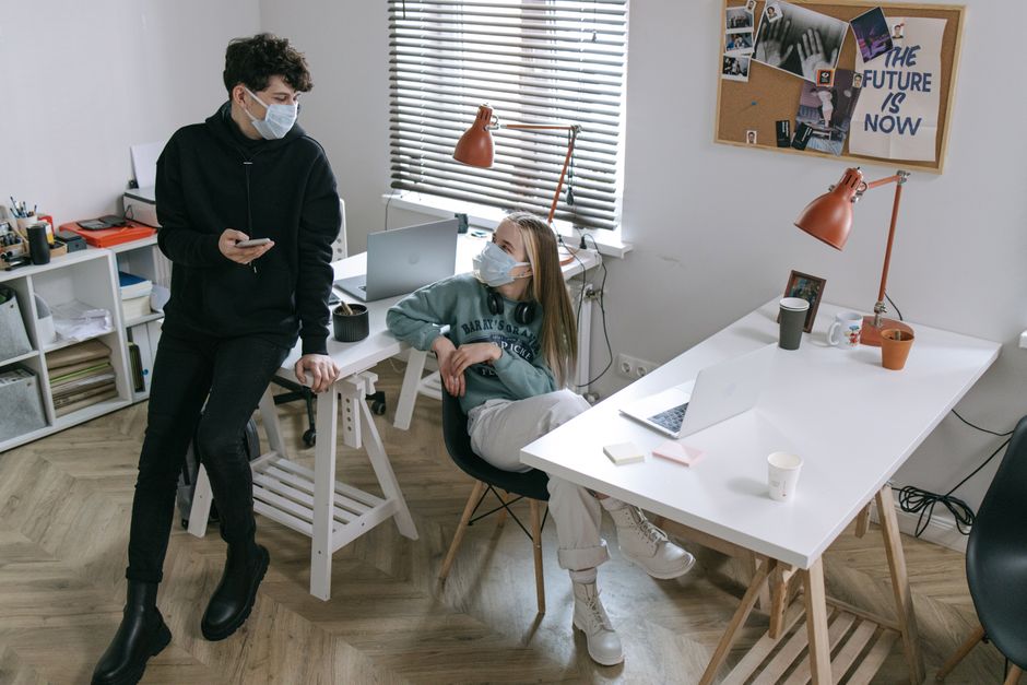 Young professionals wearing masks working at a modern office desk during COVID-19.