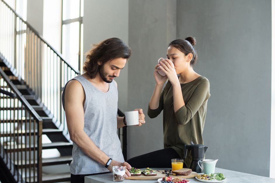 A couple enjoying a cozy breakfast with coffee and juice in their modern home kitchen.