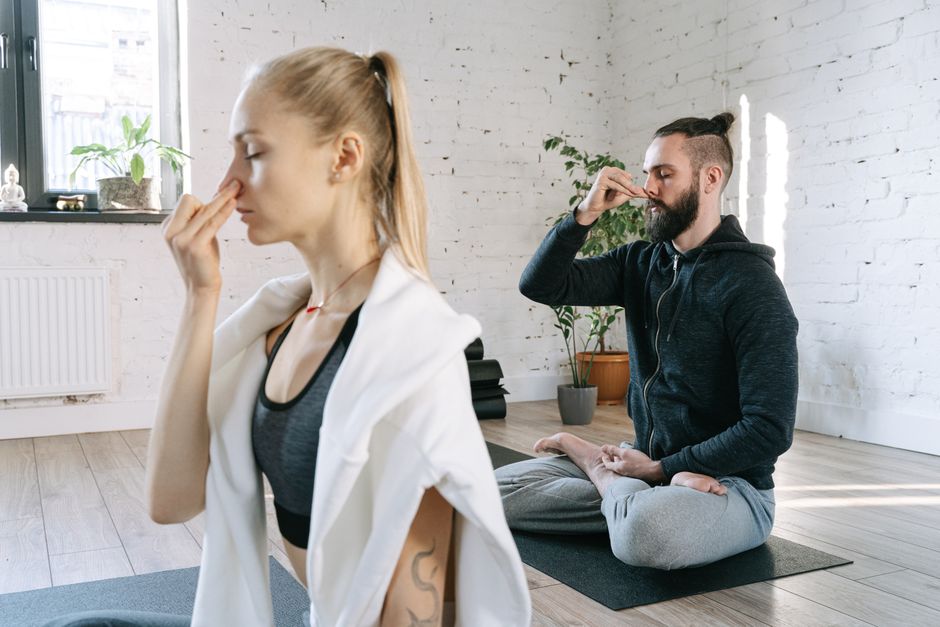 A man and woman practicing mindful yoga and breathing exercises in a serene indoor setting.