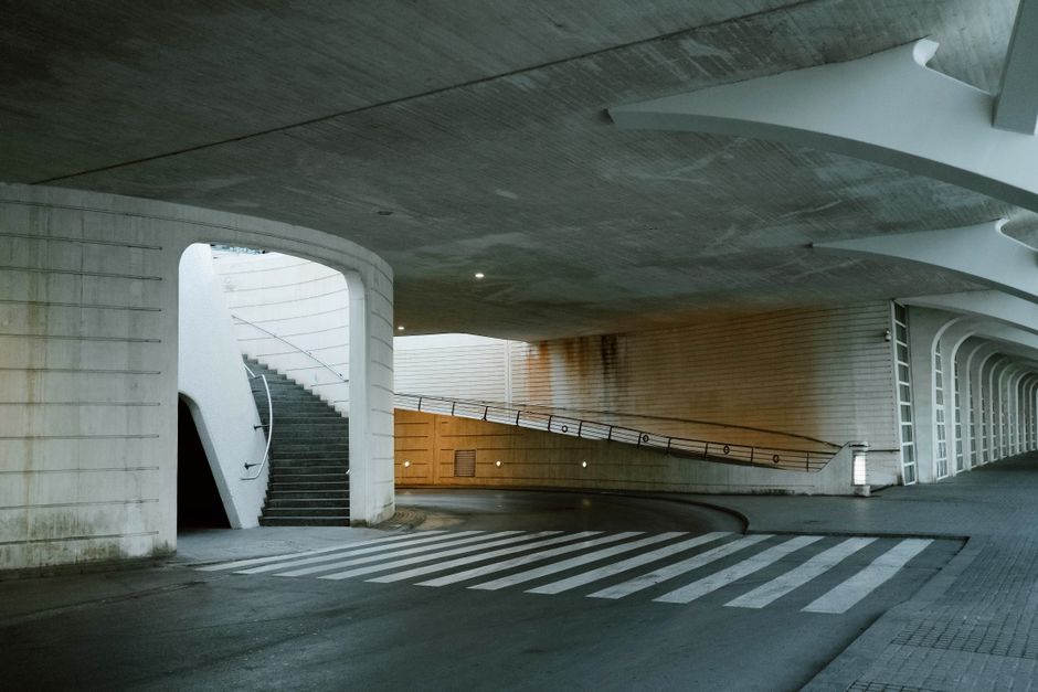 A modern underpass featuring a staircase, crosswalk, and architectural lighting in an urban setting.