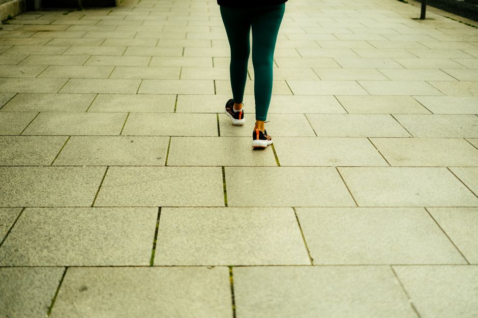A person in green leggings walks on a stone tiled sidewalk in Dublin promoting a healthy lifestyle.