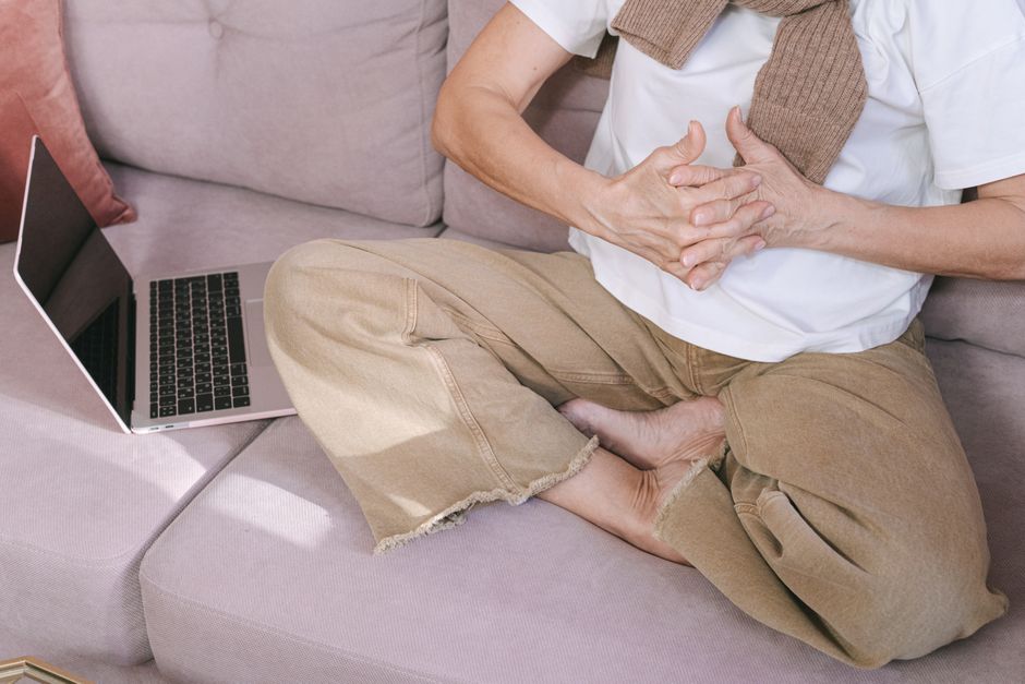 A person meditating on a couch with a laptop, embodying relaxation and technology balance.