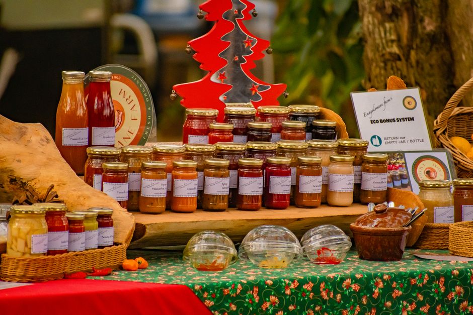 A vibrant display of homemade jams in jars at a festive market table, featuring seasonal decor.