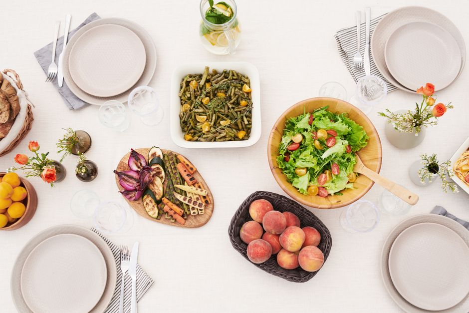 A vibrant summer table setting featuring grilled vegetables, fresh peaches, and a garden salad.