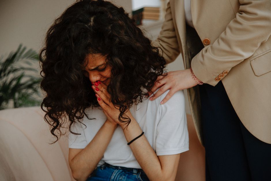 A young woman receiving comforting and emotional support during a therapy session.