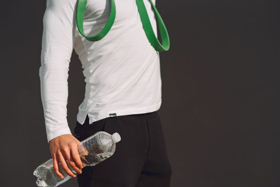 An individual holds a water bottle and fitness band, showcasing a healthy lifestyle and exercise readiness.