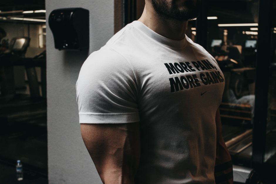 Close-up of a muscular man in a t-shirt training in an indoor gym setting.