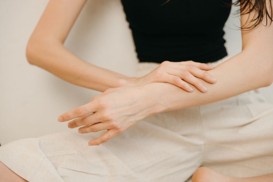 Close-up of a woman applying cosmetic cream on her arm for skincare.