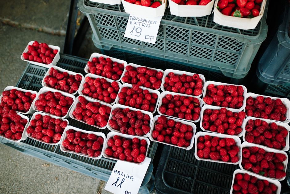 Close-up of fresh red raspberries in white cartons at a market stall. High-angle view.