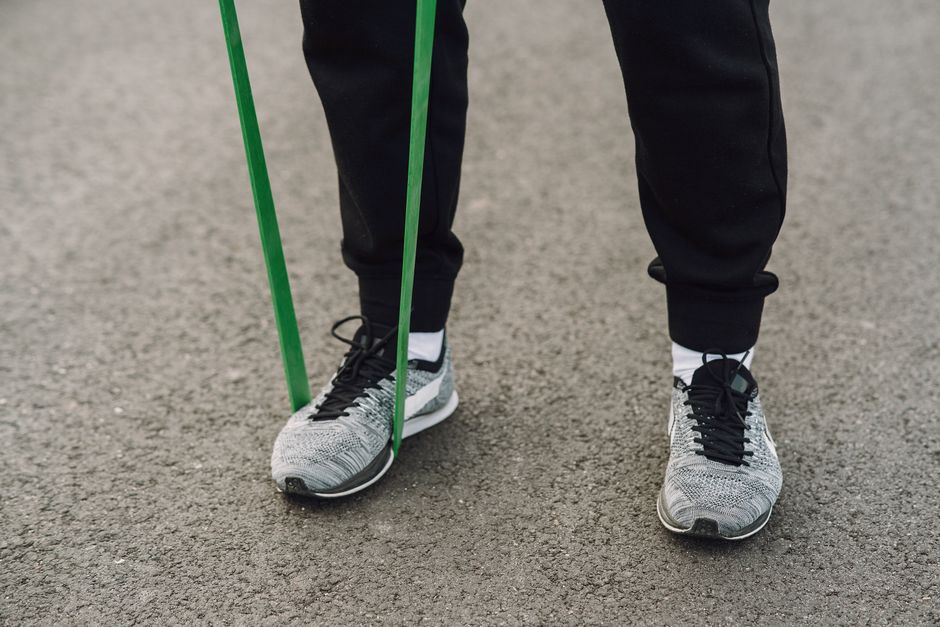 Close-up of person using a green resistance band during an outdoor workout.