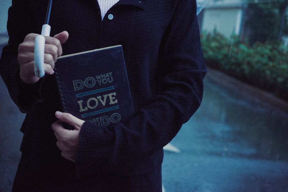 Close-up of person with umbrella holding a notebook on a rainy day.