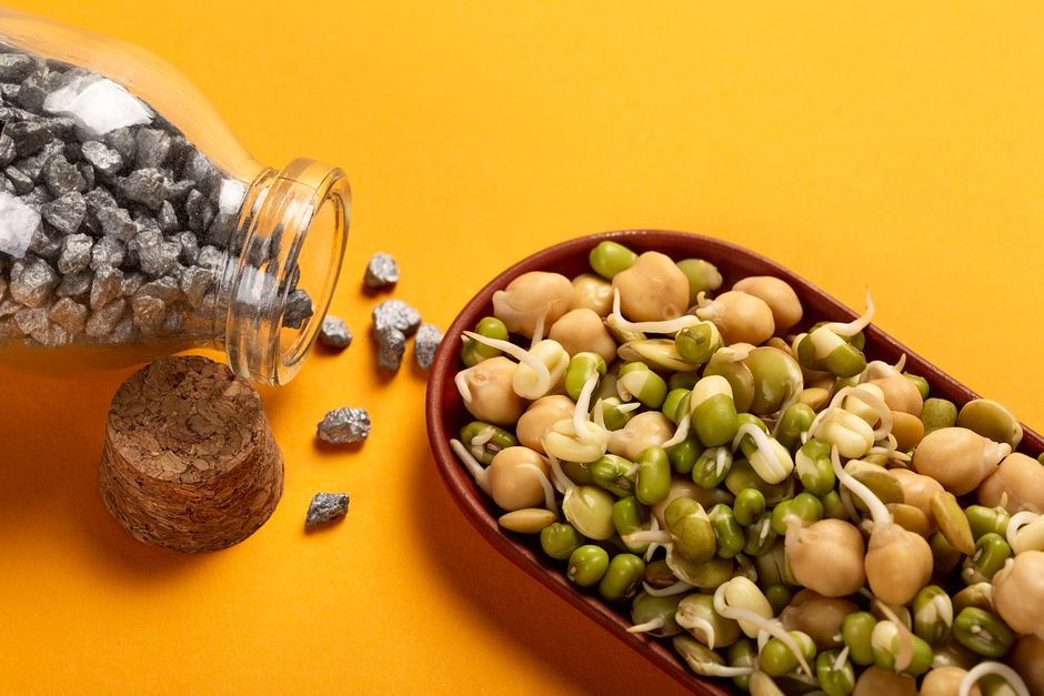 Healthy sprouted chickpeas and beans with iron nuggets on a vibrant yellow backdrop.