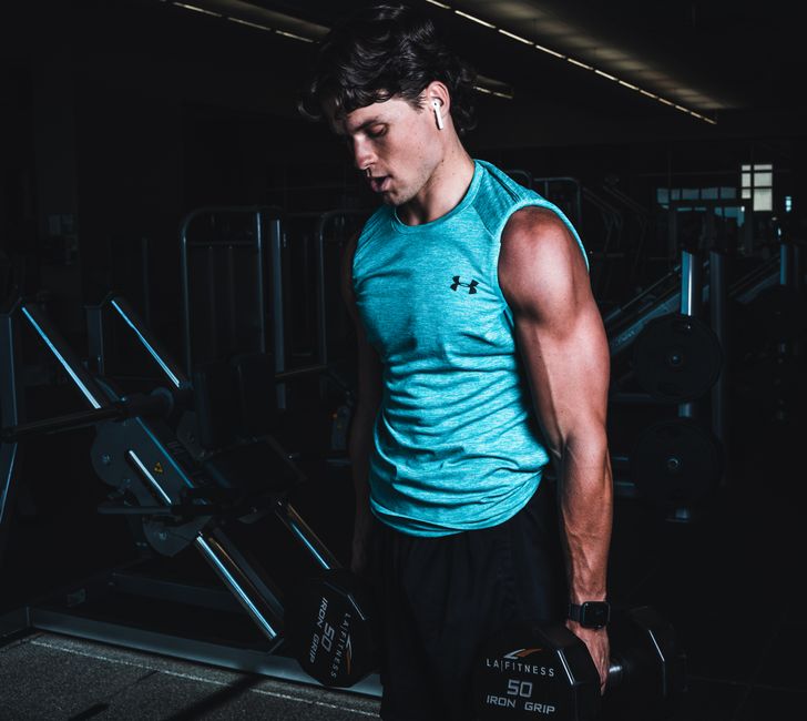 Man exercising indoors, lifting dumbbells for strength training in a Towson gym.
