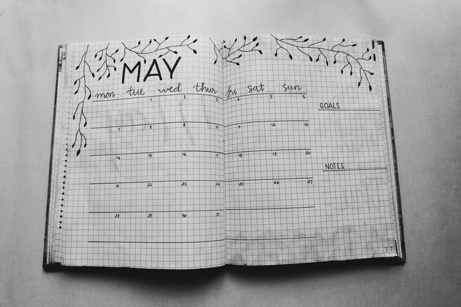 Open notebook displaying a minimalist May planner with handwritten days and decorative elements.