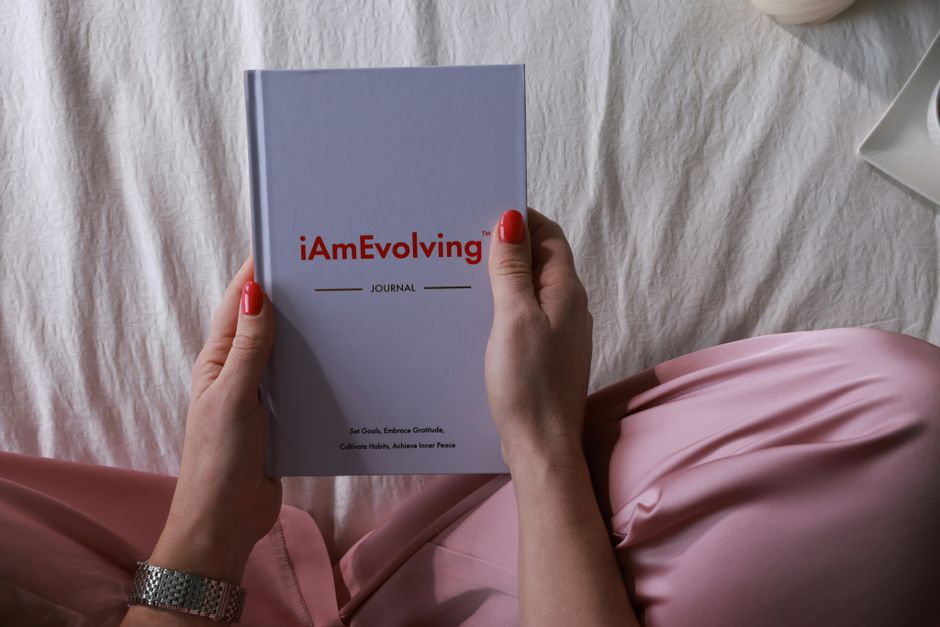 Person in pink pajamas holding a journal, embracing a cozy and mindful morning routine indoors.