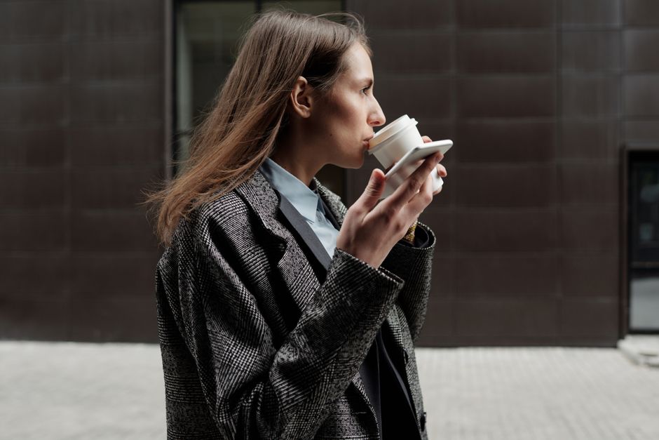 Professional woman enjoying a coffee break outside in a modern city environment.