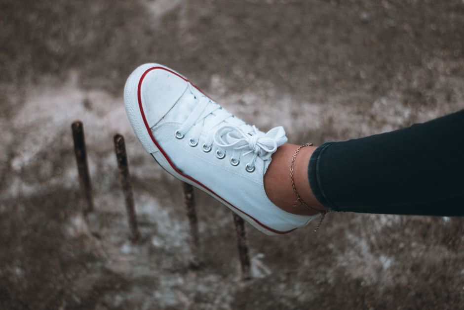 Stylish close-up of a white sneaker with red trim against an outdoor textured background.