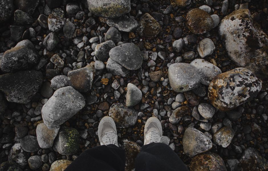 Top-down view of sneakers on a textured rock surface, showcasing footwear contrast.