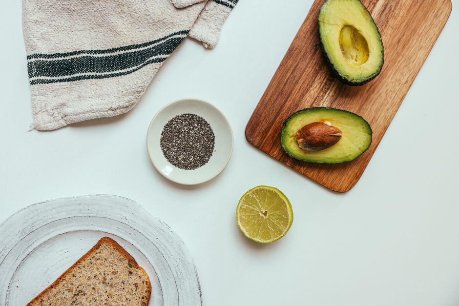 Top view of a fresh avocado, chia seeds, and sliced bread for a healthy meal.