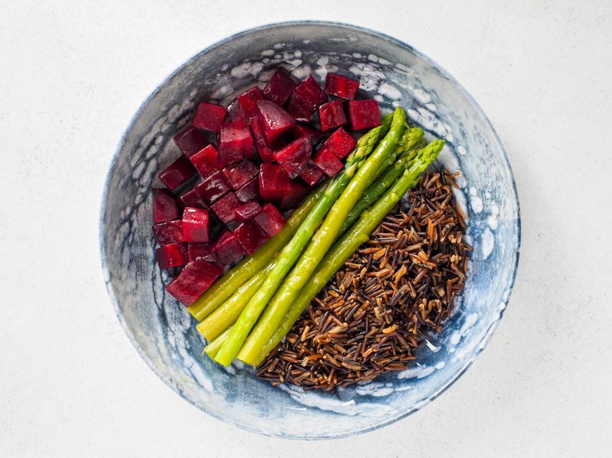 Top view of a nutritious vegan meal featuring beets, asparagus, and wild rice in a decorative bowl.