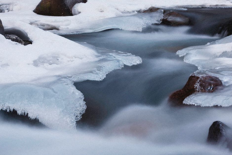 Tranquil winter scene of a frozen stream with snow and ice.