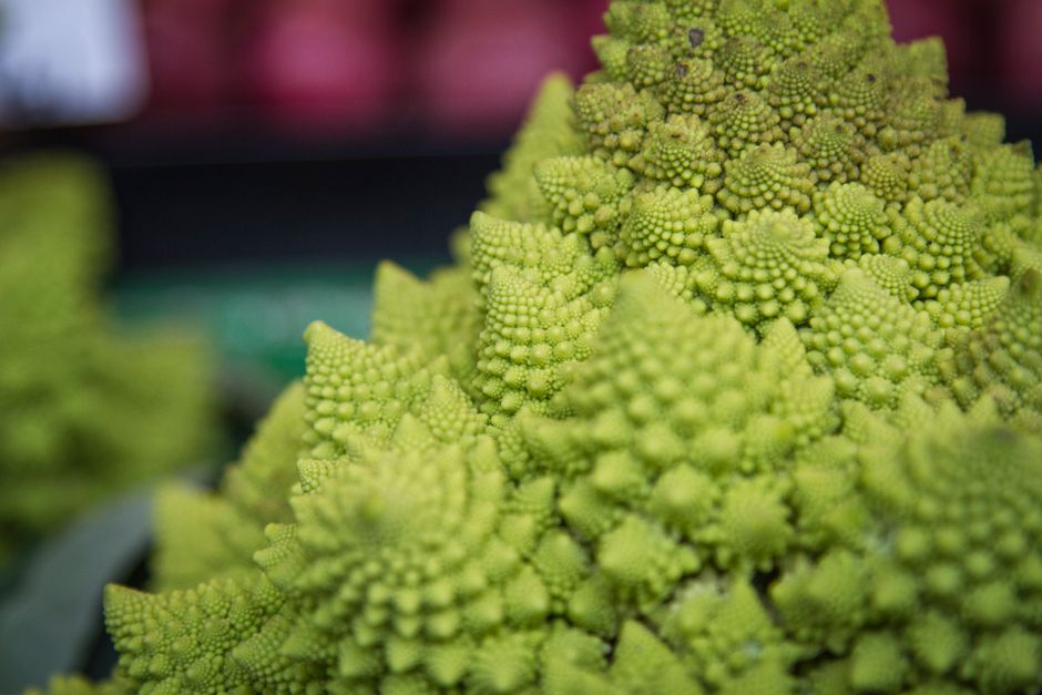 Vibrant close-up of Romanesco broccoli with intricate patterns at a market.