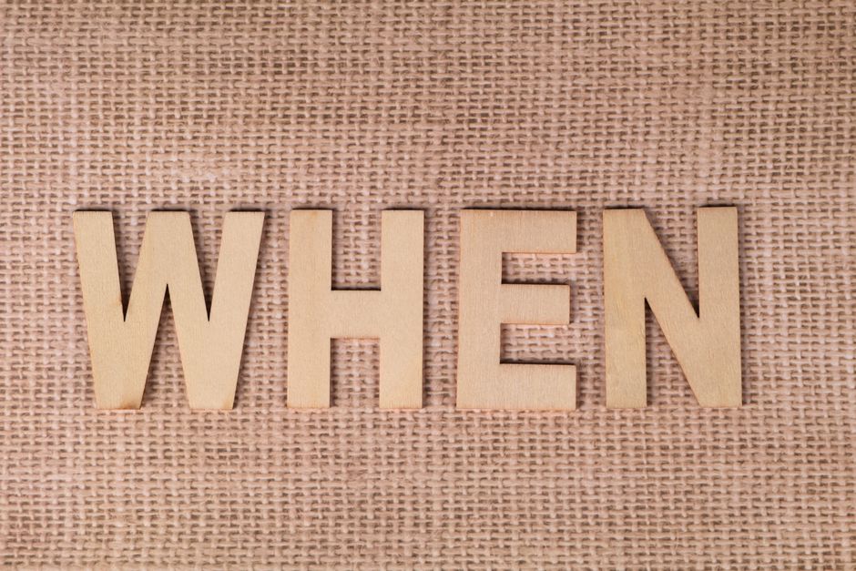 Wooden letters spelling "WHEN" on a textured burlap surface, ideal for concepts of time and planning.