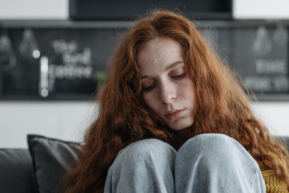 A close-up portrait of a thoughtful woman with red hair, conveying deep emotion and introspection.