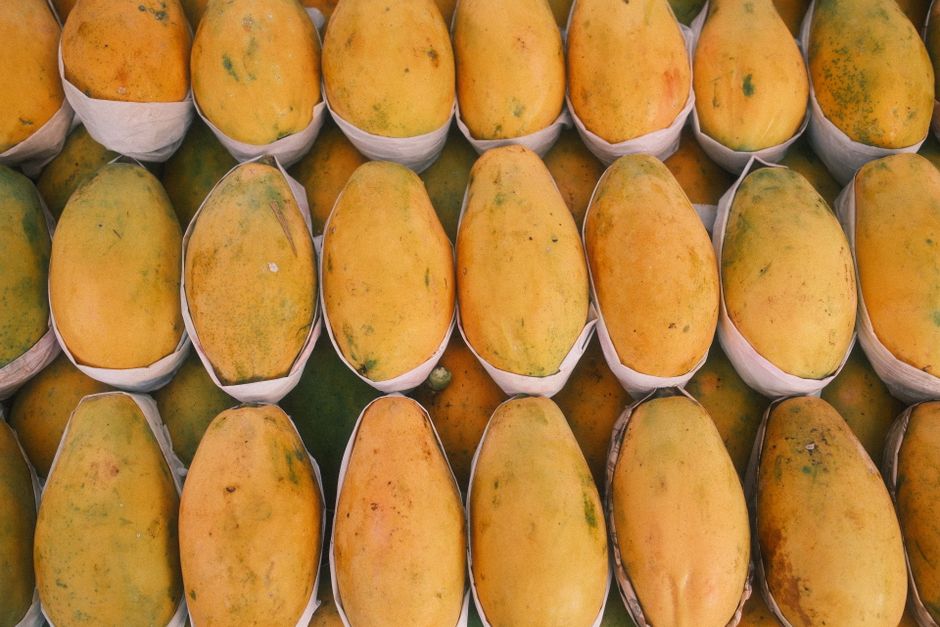 A vibrant display of ripe, yellow mangoes neatly arranged in a market setting.