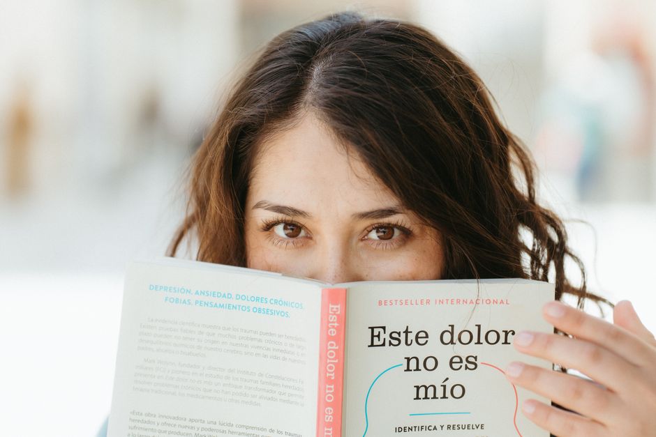 A woman reading a book titled 'Este dolor no es mío', focusing on mental health awareness.